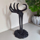 3D printed skeleton hand headphone stand in black holding gaming headphones